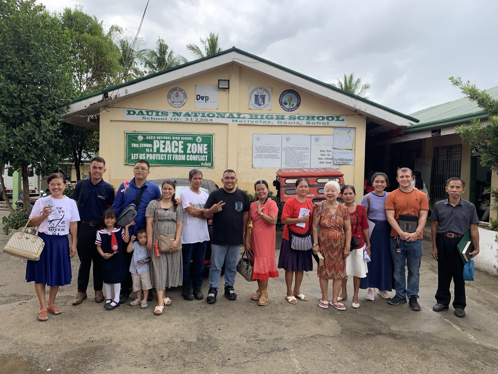 A team of Bible Baptist Church members and missionaries standing in front of Dauis National High School after a ministry visit